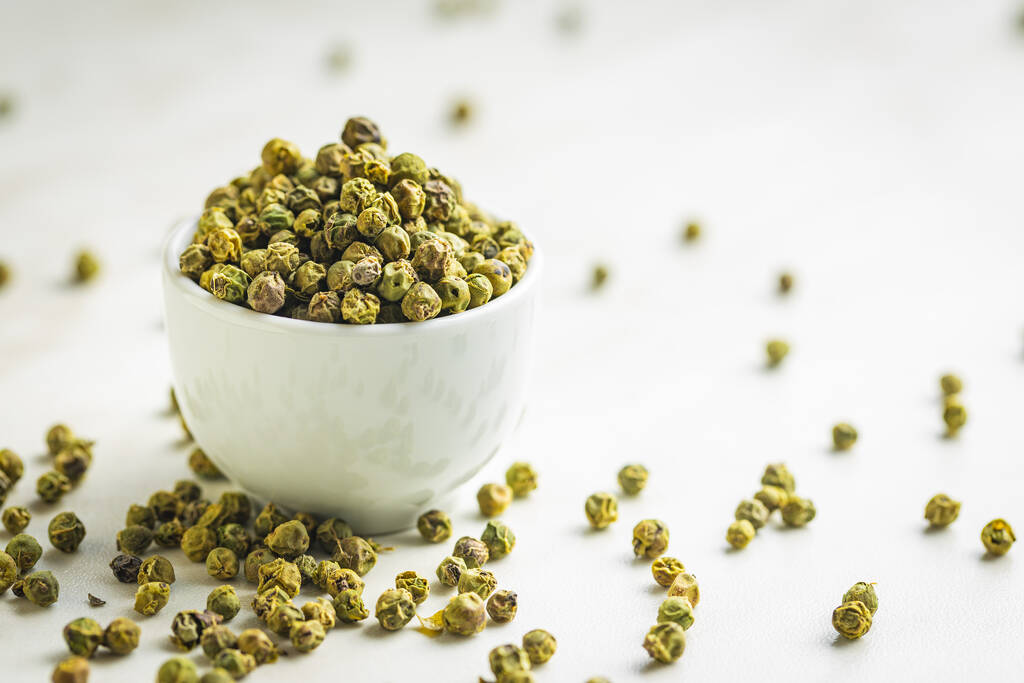 Dried green peppercorn. Dry green pepper spice in bowl on a white table. - Photo, Image