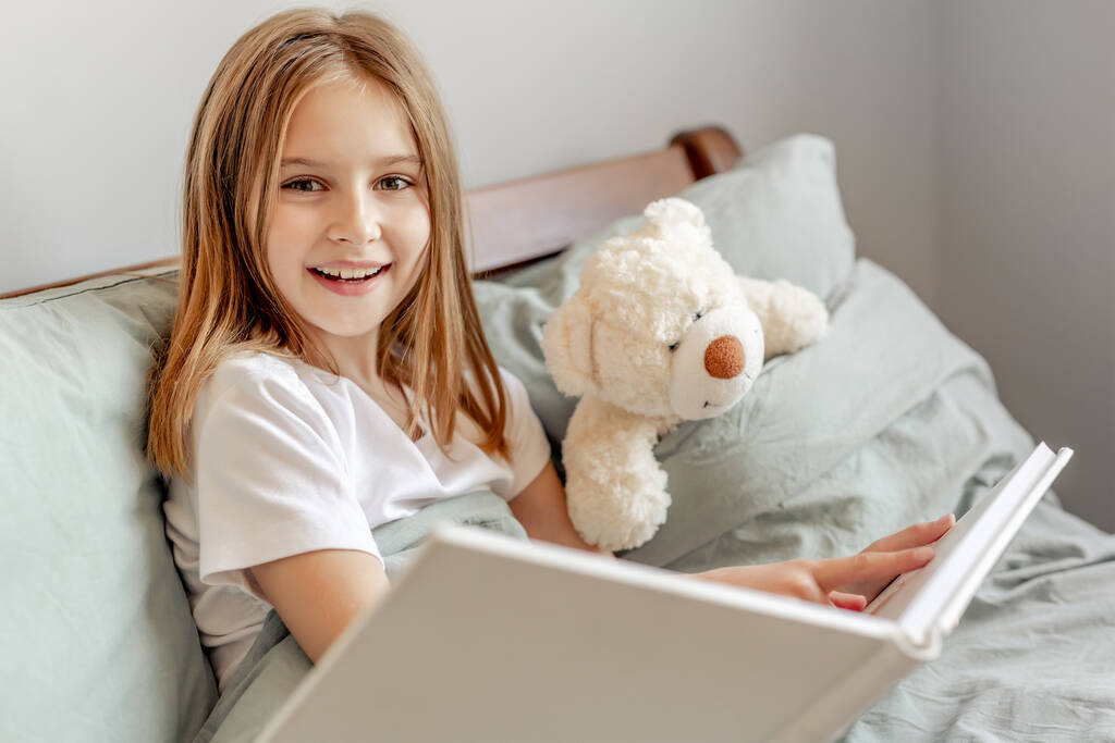 Child girl with teddy bear toy in the bed - Photo, Image