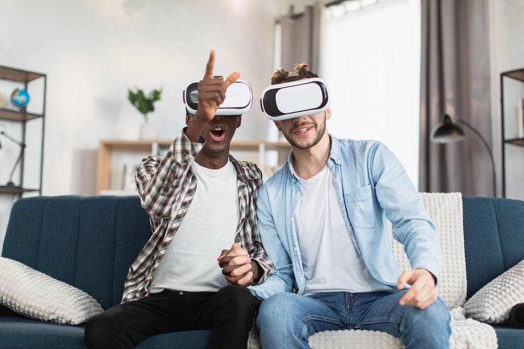 Pareja del mismo sexo usando gafas VR durante el tiempo libre en casa - Foto, imagen