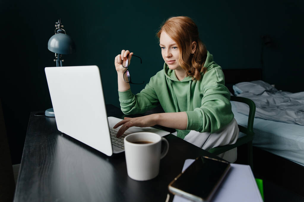 fiatal vörös hajú nő dolgozik otthon a laptop - Fotó, kép