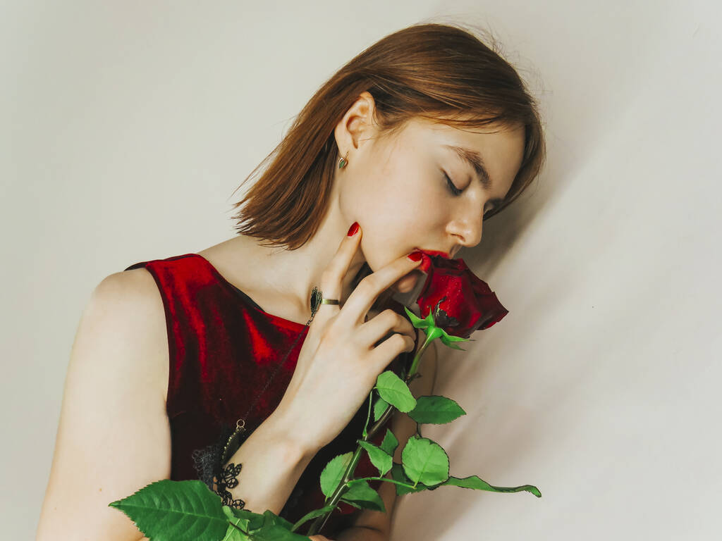 Retrato de una hermosa joven con una rosa roja, el concepto de vacaciones, 8 de marzo, fechas románticas y reuniones, regalos para las mujeres queridas, Día de San Valentín - Foto, imagen