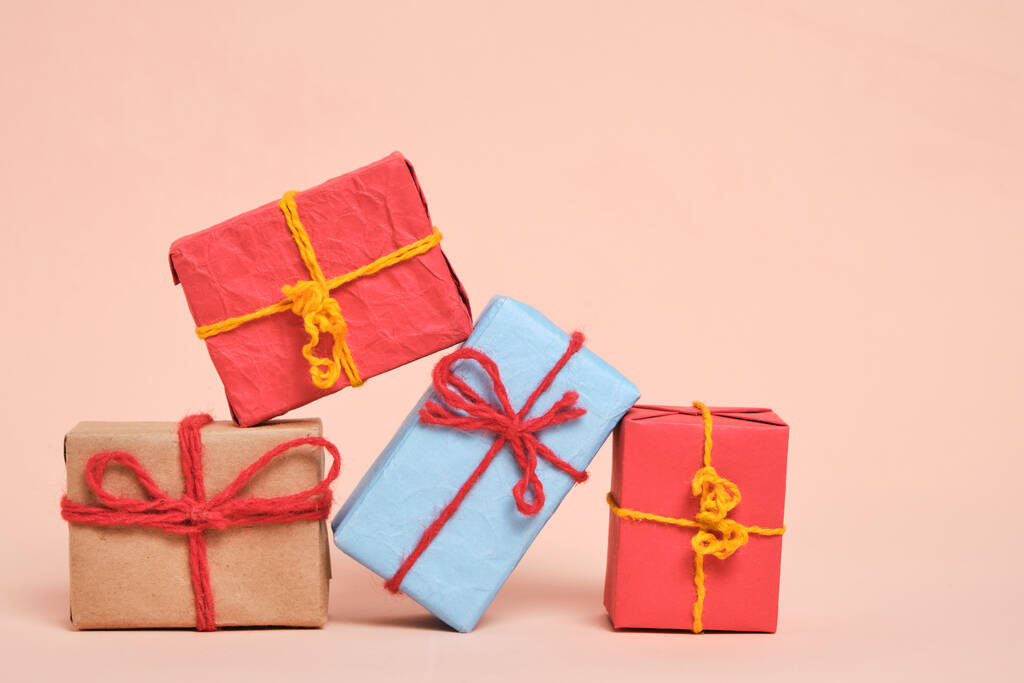 Подарки упакованы в разноцветную бумагу на пастельно-бежевом фоне. - Фото, изображение