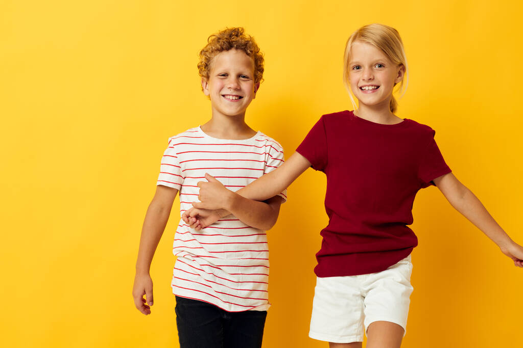 Kleine kinderen casual slijtage spelletjes leuk samen gele achtergrond - Foto, afbeelding