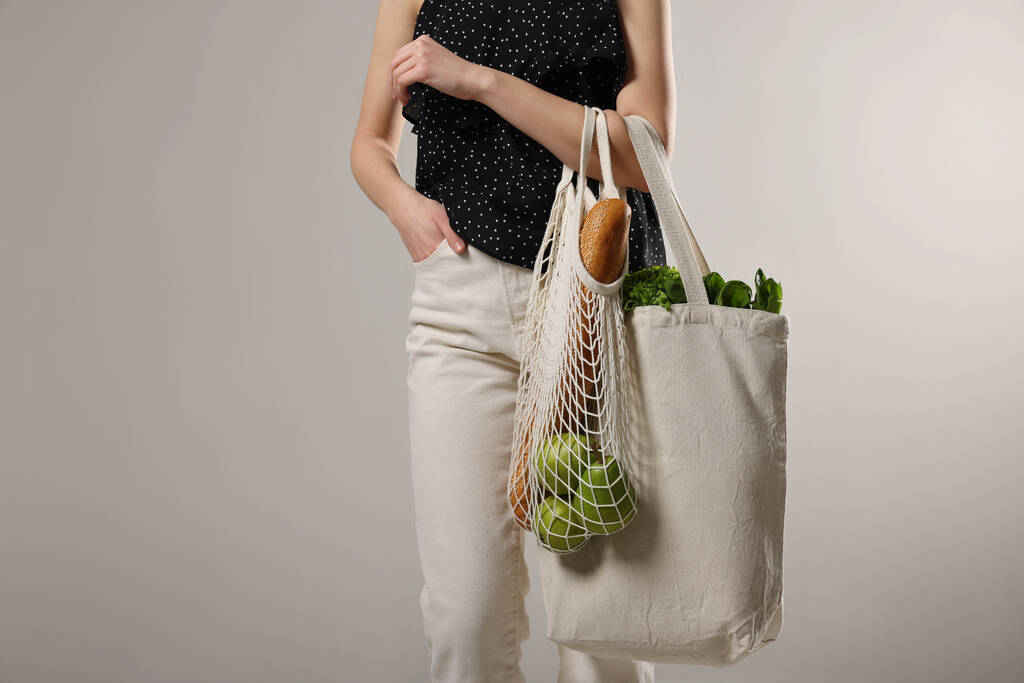 Женщина с эко-сумками, полными продуктов на светлом фоне, крупным планом - Фото, изображение