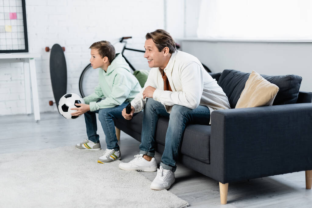 Позитивний батько і дитина дивиться футбольний матч на дивані
  - Фото, зображення