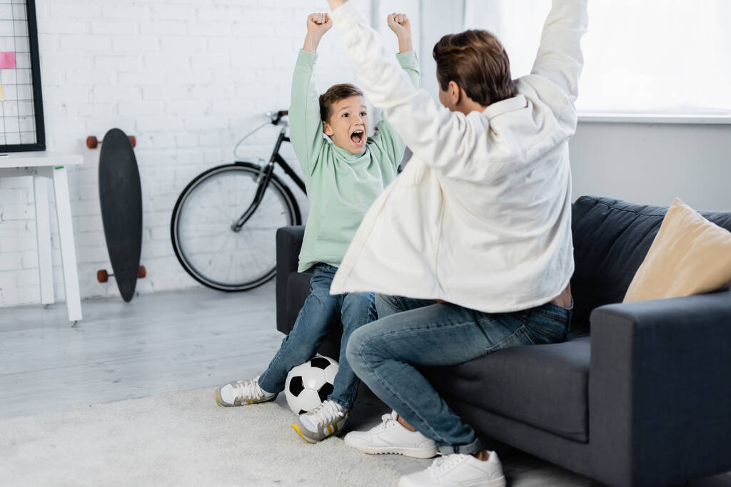 Poika ja isä osoittavat kyllä ele lähellä jalkapalloa kotona  - Valokuva, kuva