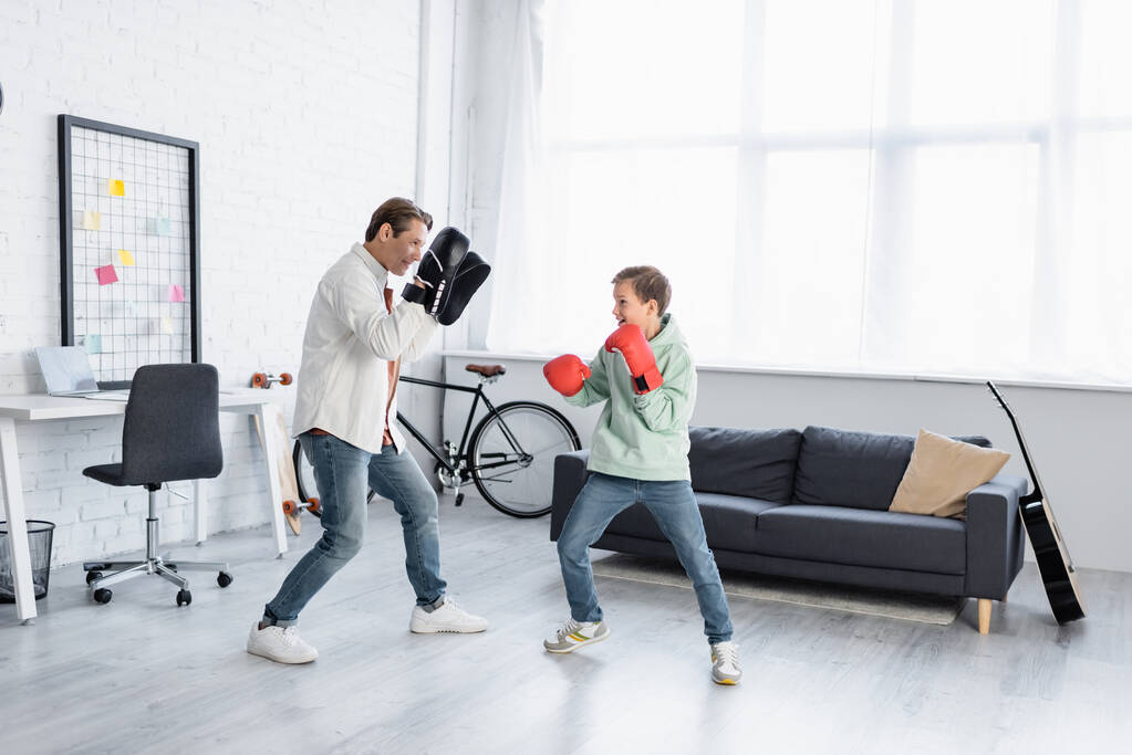 Isä ja poika nyrkkeilyhanskat koulutus olohuoneessa  - Valokuva, kuva