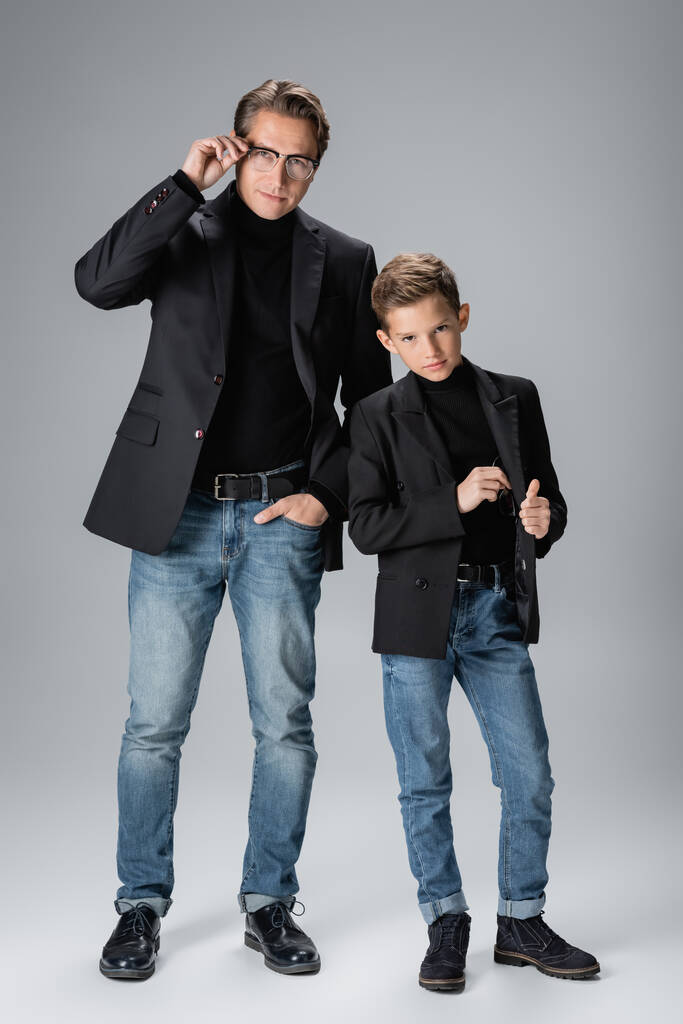 Longitud completa de papá e hijo de moda posando sobre fondo gris  - Foto, Imagen
