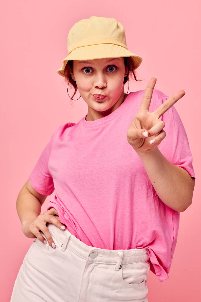 портрет молодой женщины модной одежды шляпа розовый украшение футболки позируя - Фото, изображение