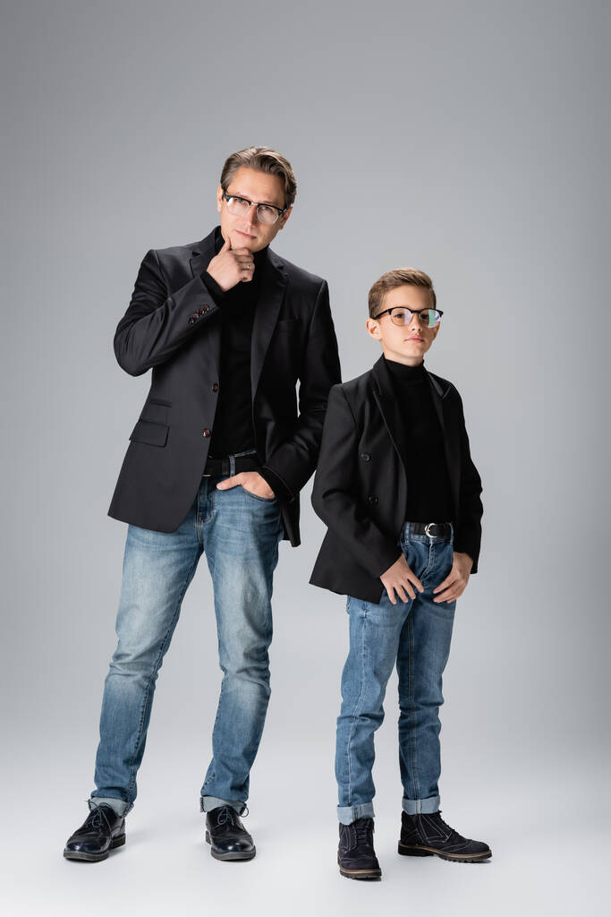 Volledige lengte van stijlvolle man en jongen poseren op grijze achtergrond  - Foto, afbeelding
