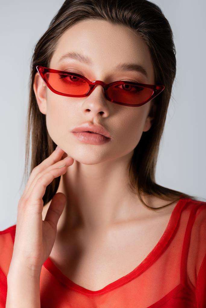 young model in red stylish sunglasses isolated on grey - Photo, Image