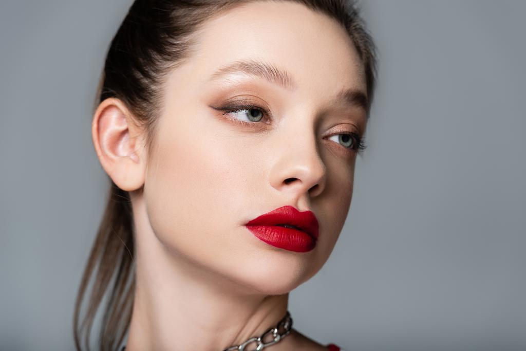 junge stylische Frau mit roten Lippen, die isoliert von grau wegschauen - Foto, Bild