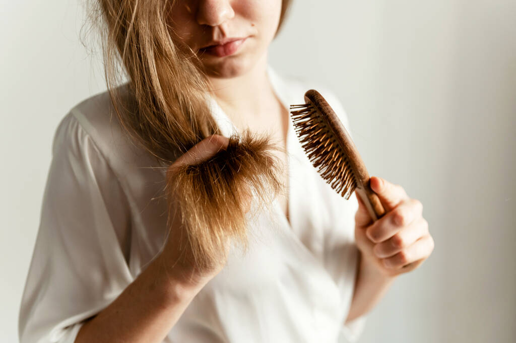 a girl with problematic hair sits on the bed and combs them. girl with a comb sits on a bed in pajamas - Photo, Image