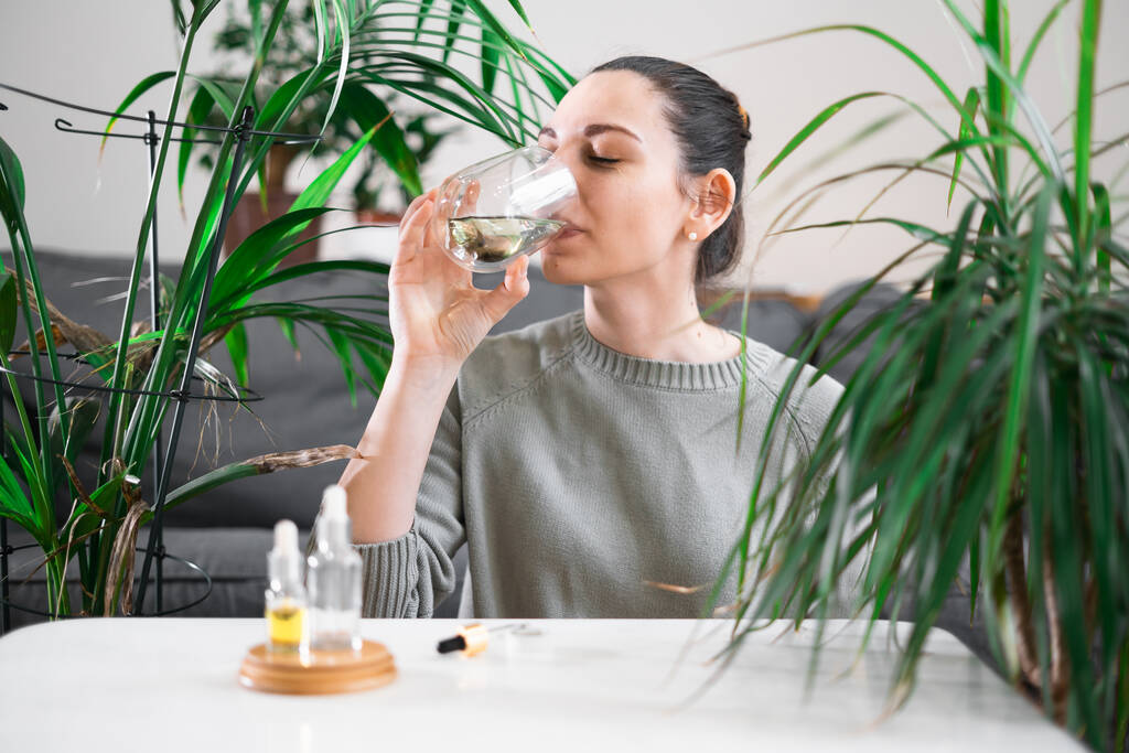 Γυναίκα πόσιμο ποτήρι με νερό χλωροφύλλη, αντιοξειδωτικό ποτό. Υγιής τρόπος ζωής  - Φωτογραφία, εικόνα