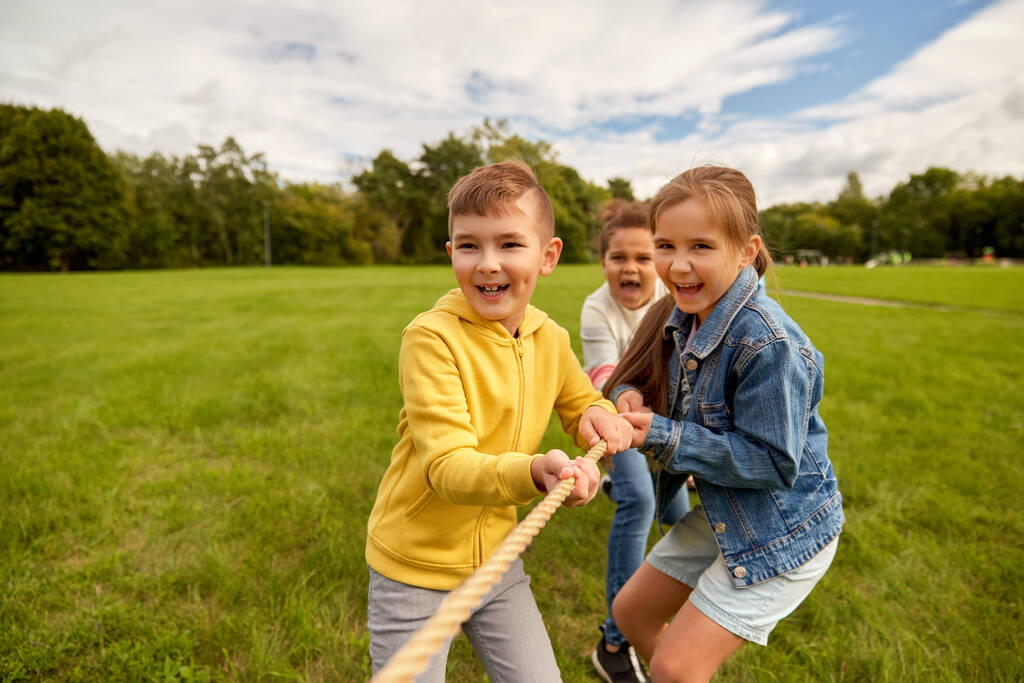 公園で綱引きゲームをしている幸せな子供たち - 写真・画像