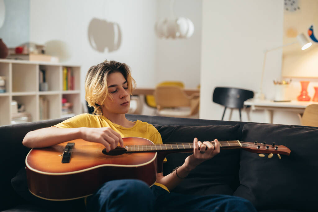 Adolescente tocando guitarra acústica em casa
 - Foto, Imagem