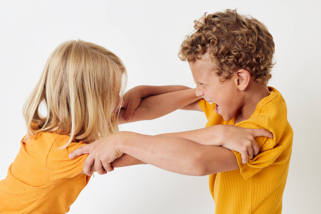 Niños pequeños con camisetas amarillas de pie lado a lado emociones infantiles fondo claro inalterado - Foto, Imagen