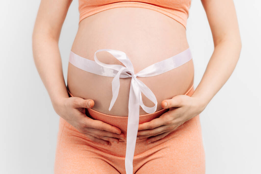 mujer embarazada con una cinta en el estómago tocando su vientre. Mujer esperando un bebé, mujer embarazada feliz con vientre grande. El concepto de embarazo, maternidad, preparación y expectativa - Foto, Imagen