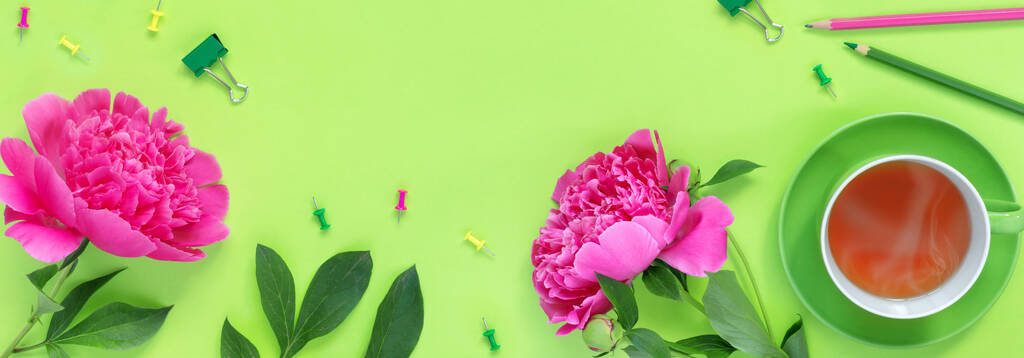 Απομακρυσμένο γραφείο στο πράσινο γραφείο και τα είδη γραφείου Μπουκέτο με όμορφα ευαίσθητα ροζ παιώνιες και φλιτζάνι ζεστό τσάι για τις διακοπές. - Φωτογραφία, εικόνα