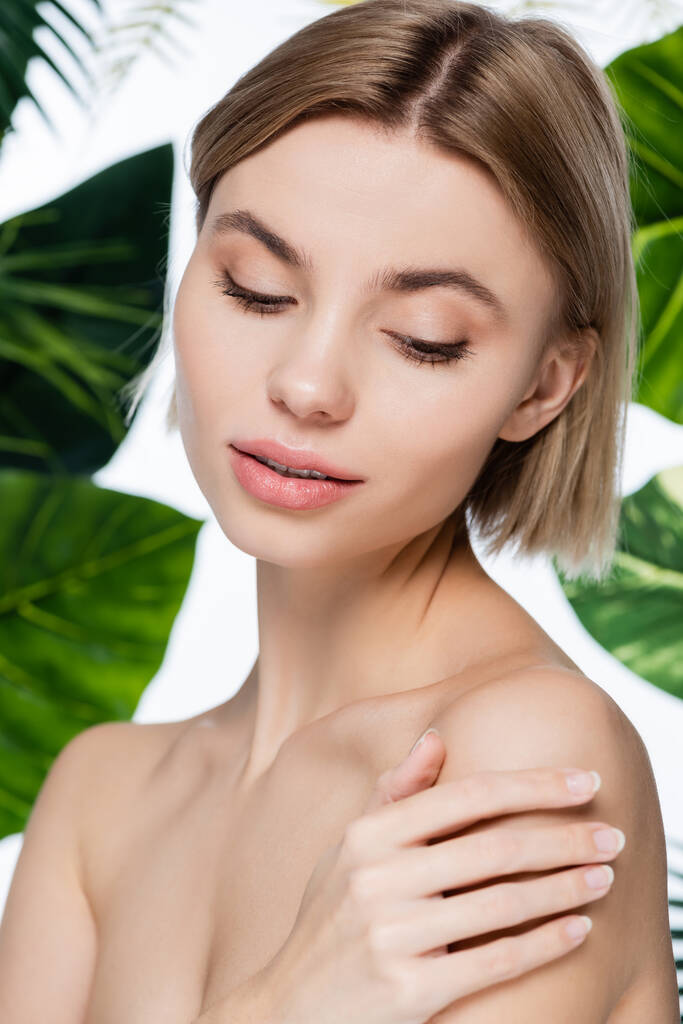чуттєва молода жінка з ідеальною шкірою біля зеленого пальмового листя на білому
 - Фото, зображення