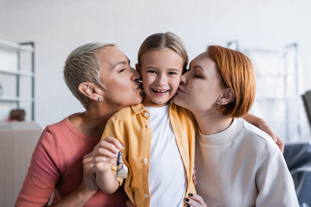 pareja del mismo sexo besando feliz hija adoptada sosteniendo la llave de nuevo apartamento - Foto, imagen
