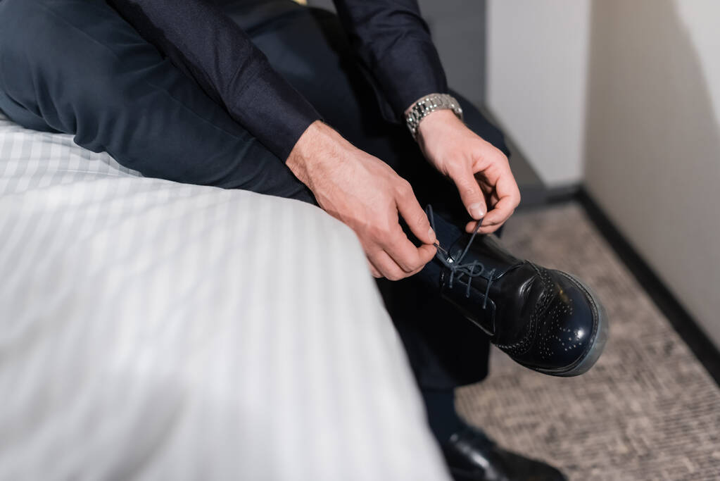 bijgesneden beeld van de man veters binden op schoenen in hotel - Foto, afbeelding