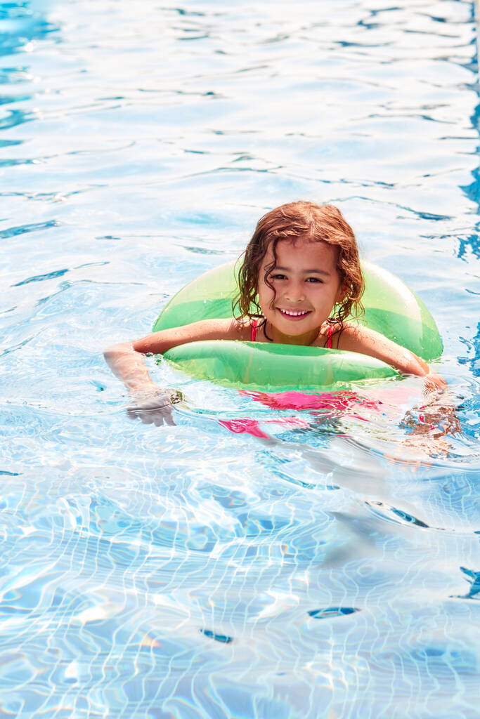 Młoda dziewczyna uczy się pływać z nadmuchiwanym pierścieniem w basenie na wakacjach - Zdjęcie, obraz