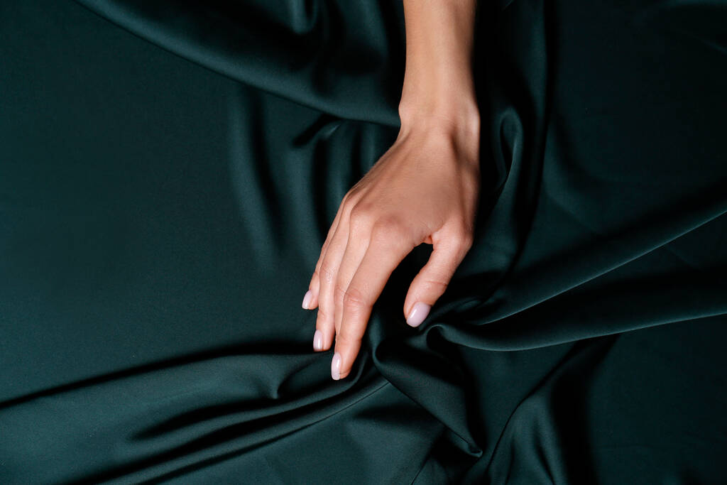 Woman touching soft dark green fabric, top view - Photo, Image