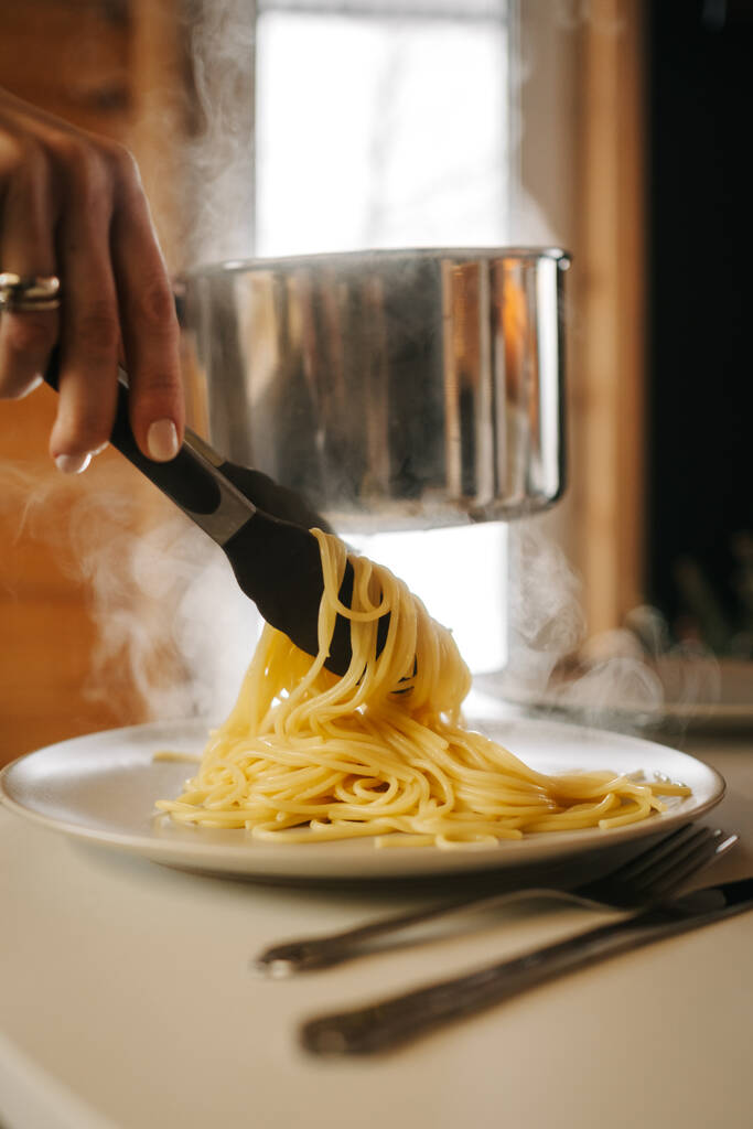 Kız spagetti koyuyor. Buhar geliyor. Yüksek kalite fotoğraf - Fotoğraf, Görsel
