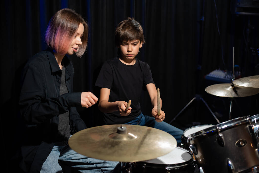 Молодая женщина учит мальчика играть на барабанах. - Фото, изображение