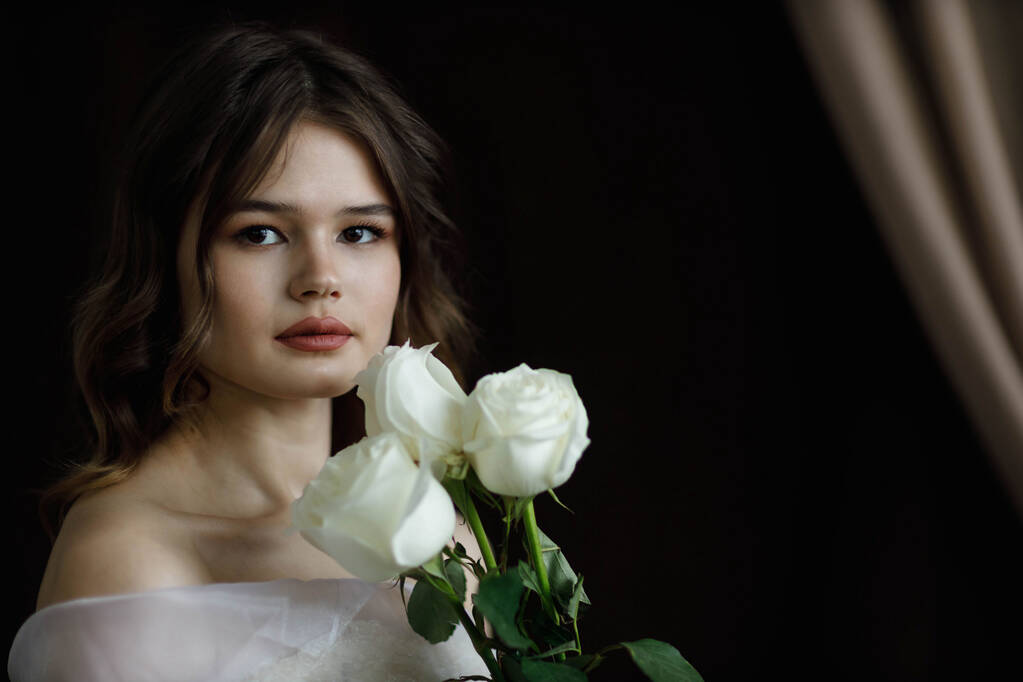 Una ragazza con rose bianche, girata in uno studio con luce da una finestra - Foto, immagini