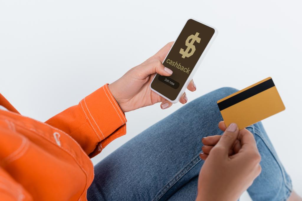 Teilansicht der Frau mit Smartphone, Bargeld auf dem Bildschirm und Kreditkarte isoliert auf grau  - Foto, Bild