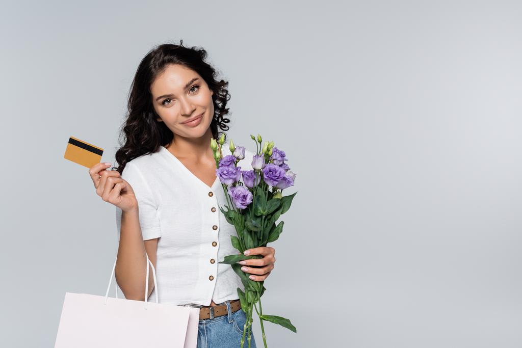 Elinde çiçek buketi, alışveriş çantası ve kredi kartı tutan mutlu bir kadın.  - Fotoğraf, Görsel