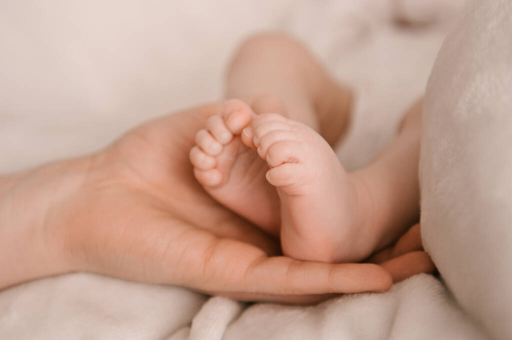 Маленькие ножки новорожденной девочки в руке Папы на светлом фоне - Фото, изображение