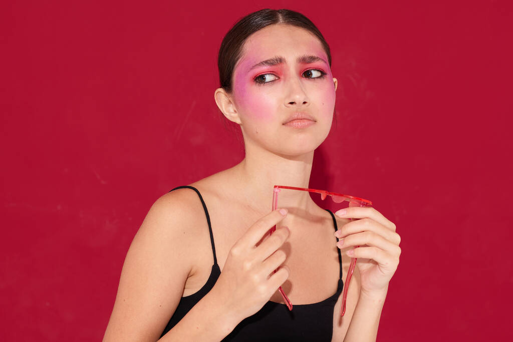 Nuori kaunis nainen vaaleanpunainen lasit meikki tunteita kosmetiikka eristetty tausta muuttamaton - Valokuva, kuva