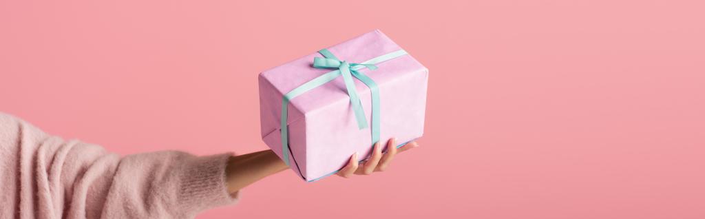 kivágott kilátás fiatal nő gazdaság csomagolt ajándékdoboz elszigetelt rózsaszín, banner - Fotó, kép
