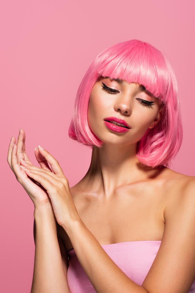 αισθησιακή νεαρή γυναίκα με χρωματιστά μαλλιά και αφέλειες κοιτάζοντας μακριά απομονωμένη σε ροζ  - Φωτογραφία, εικόνα