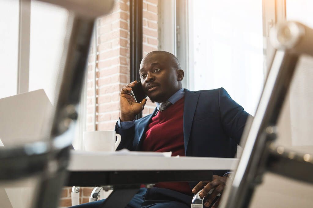 Egy afro-amerikai portréja az irodában. Fekete férfi egy üzleti öltönyben, aki laptopon dolgozik. - Fotó, kép