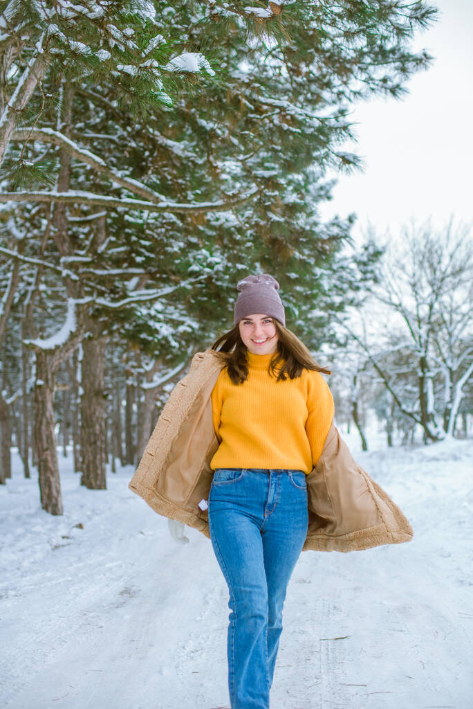 Молодая симпатичная девушка веселится в снежную погоду зимой в парке. Стиль жизни  - Фото, изображение