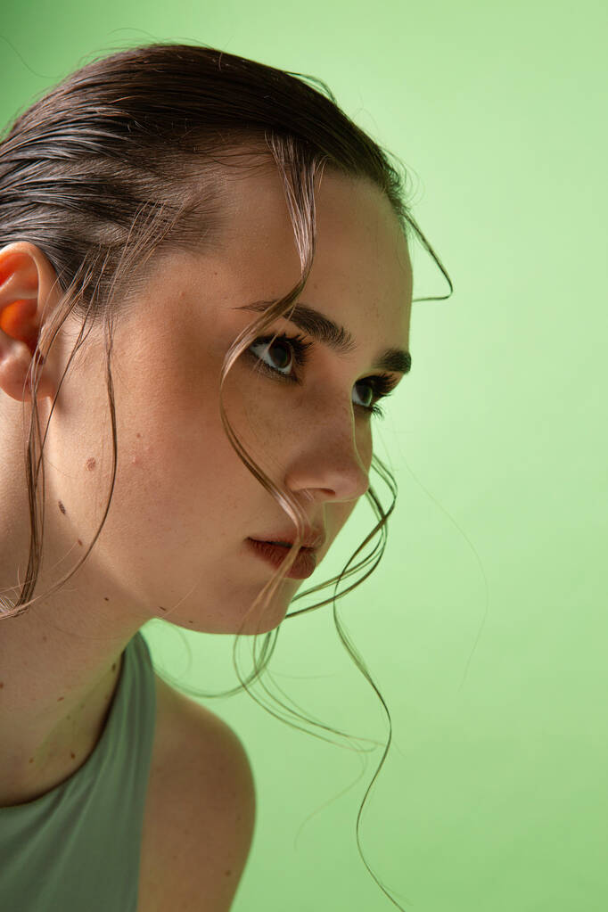 緑に隔離された濃い髪を集めた強い若い女性の肖像画 - 写真・画像