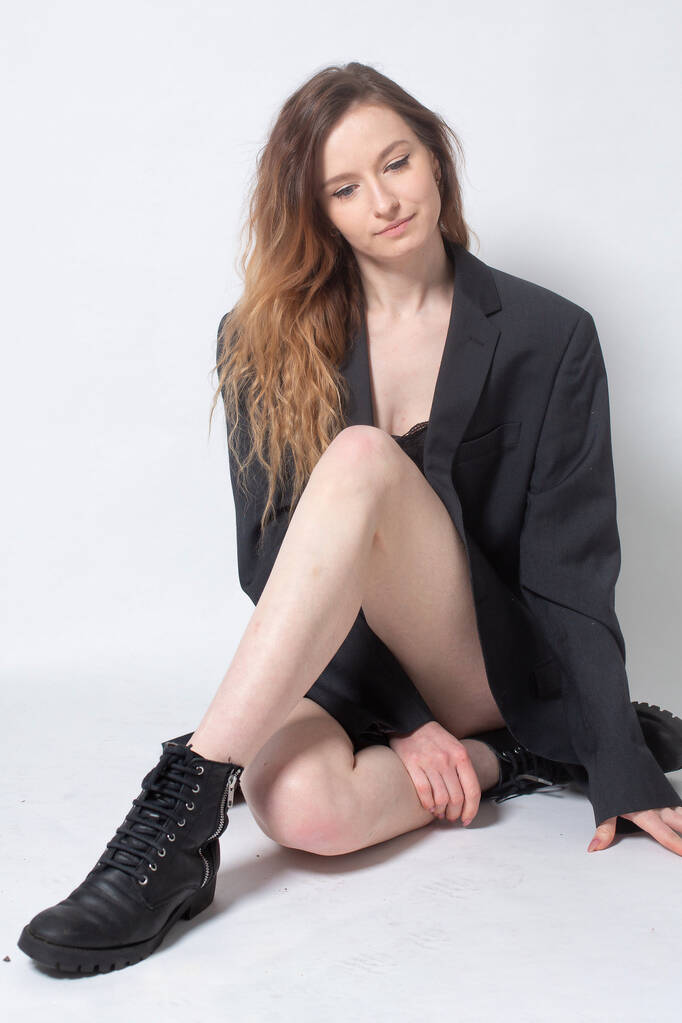 Fehér fiatal európai nő barna haj ül fekete a padlón elszigetelt világosszürke - Fotó, kép