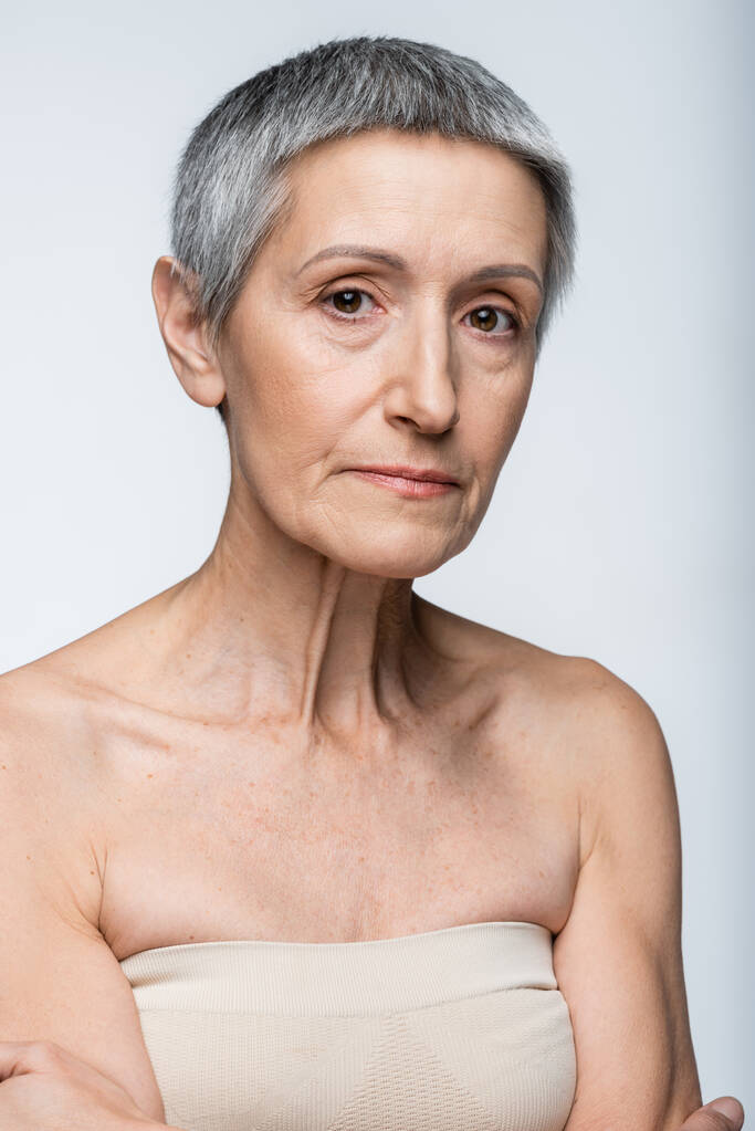 mujer madura con pelo gris y arrugas aisladas en gris - Foto, Imagen