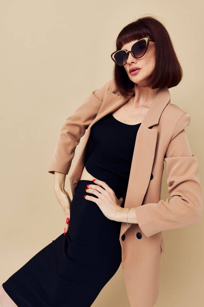 attraktive Frau in einer beigen Jacke eleganten Stil Sonnenbrille isolierten Hintergrund - Foto, Bild