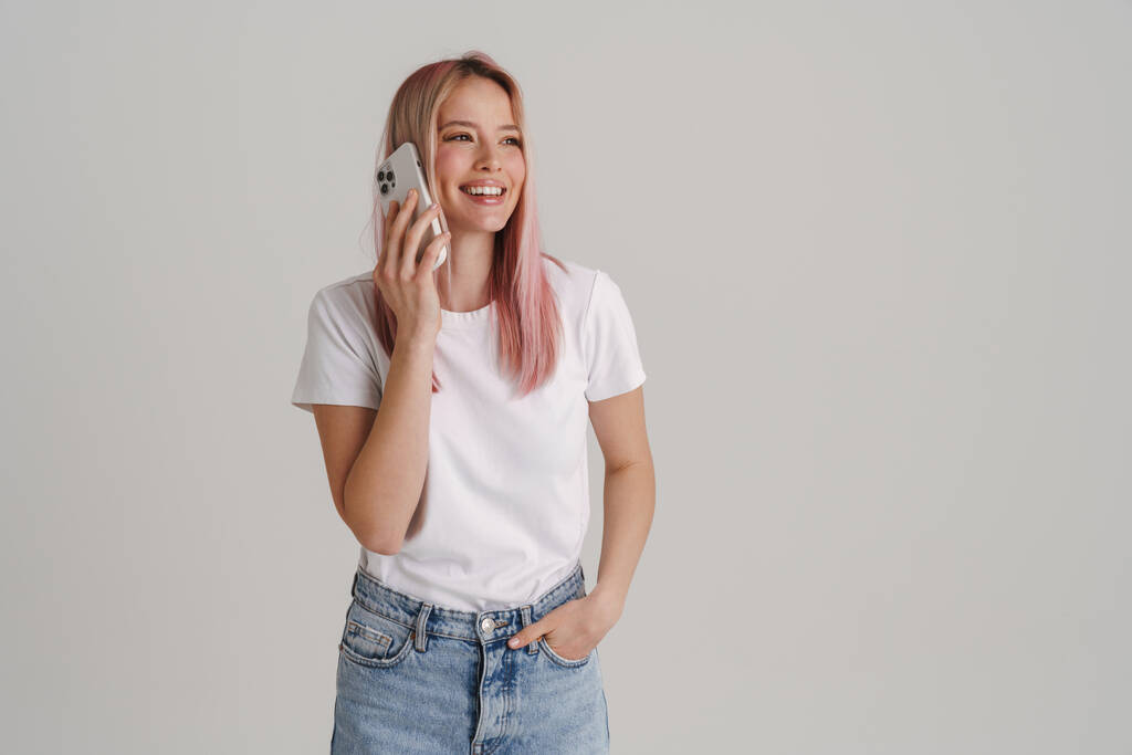 Νεαρή Ευρωπαία γυναίκα χαμογελά μιλώντας στο κινητό τηλέφωνο απομονωμένη σε λευκό φόντο - Φωτογραφία, εικόνα