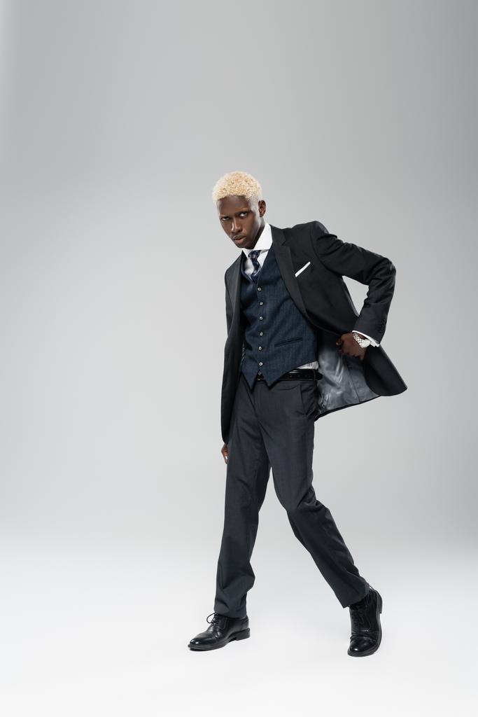 full length of elegant african american man in formal wear posing on grey - Photo, Image
