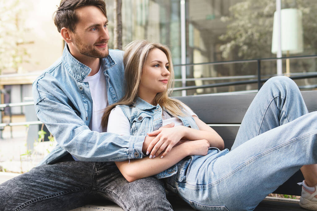 Ritratto di giovane coppia sensuale e amorevole seduta sulla panchina durante un appuntamento all'aperto - Foto, immagini