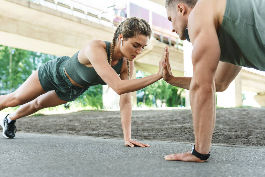 Urheilupariskunta ja kuntoilu ulkona. Mies ja nainen tekee push-up liikuntaa rinnassa ja triceps lihaksia aikana street workout  - Valokuva, kuva