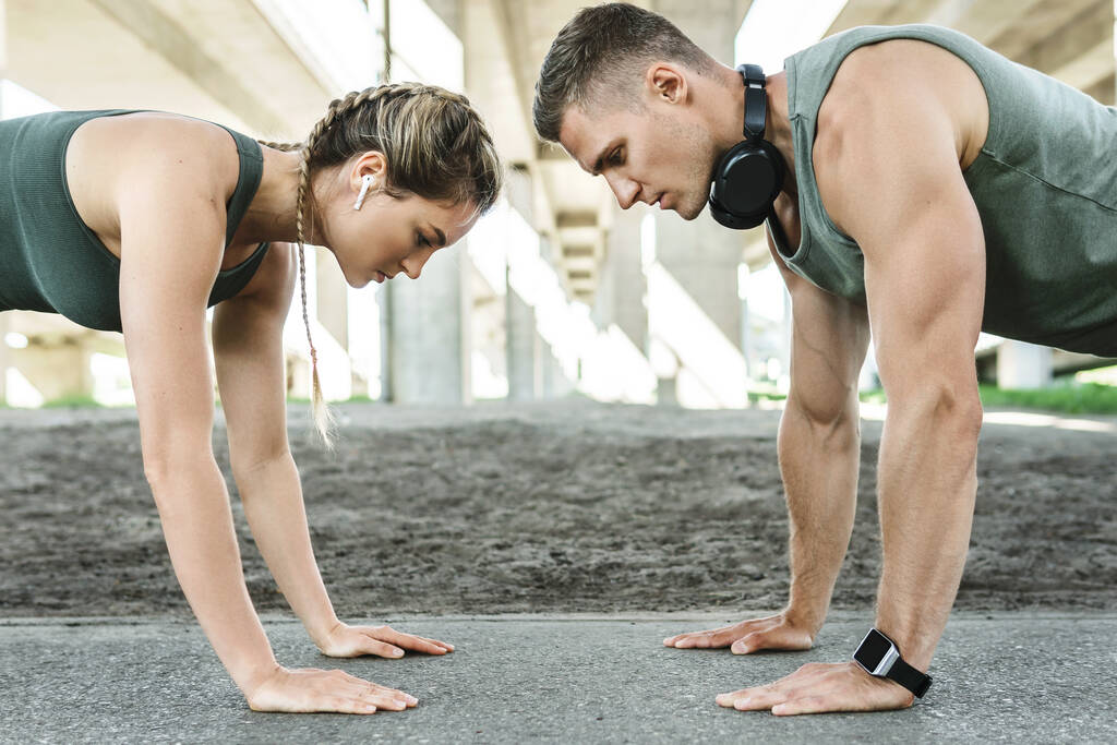 Атлетическая пара и фитнес-тренировки на открытом воздухе. Мужчина и женщина делают отжимания упражнения для груди и трицепсы мышц во время тренировки на улице  - Фото, изображение