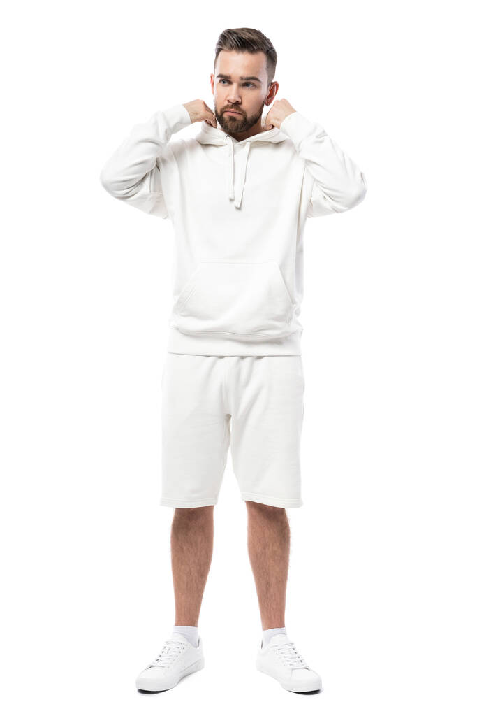 Schöner Mann mit weißem Kapuzenpulli und kurzen Hosen auf weißem Hintergrund - Foto, Bild