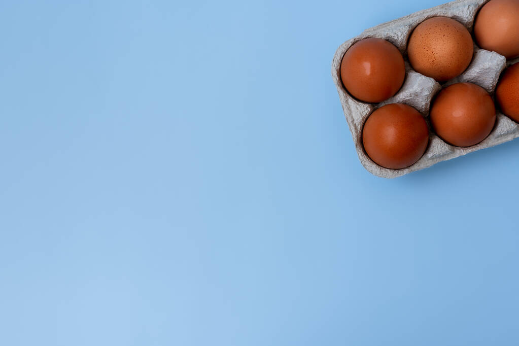 Mavi arka planda bir tepside tavuk kahverengi yumurtalar, üst manzara, düz yatış, arka plan  - Fotoğraf, Görsel